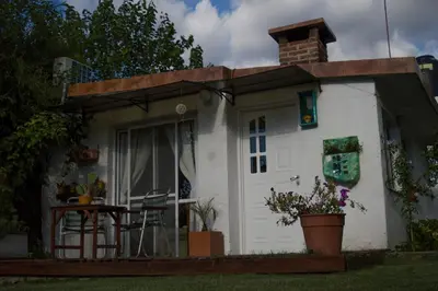 a small white house with a porch and a table at Cabaña Su Estar in Villa de Las Rosas