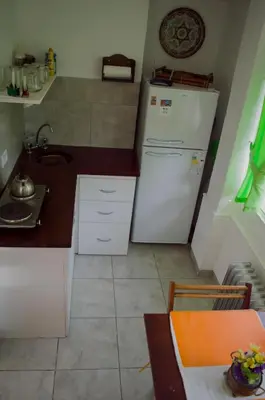 a kitchen with a white refrigerator and a table at Cabaña Su Estar in Villa de Las Rosas