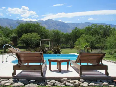 two wooden chairs and a table next to a pool at Bandera Blanca Cabañas & Suites in San Javier