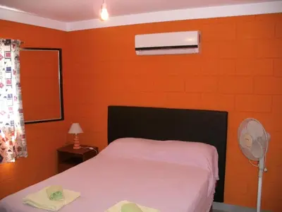 a bedroom with an orange wall with a bed and a fan at Residencia Jose Maria in Santa Rosa de Calamuchita