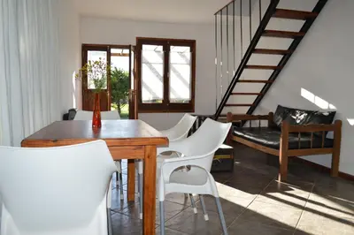 a dining room with a wooden table and white chairs at Celandine in Los Reartes