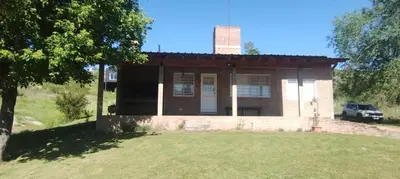 an old brick house with a car parked in front of it at El Campito casa frente al río in Villa Carlos Paz