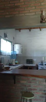 a kitchen with a counter and a sink and a stool at El Campito casa frente al río in Villa Carlos Paz