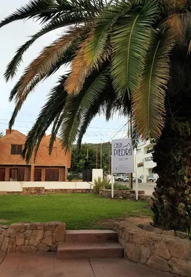 a palm tree and a sign in front of a building at Casa Piedra Hotel in Villa Carlos Paz