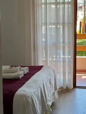 a bedroom with a bed with white sheets and a window at Casa Piedra Hotel in Villa Carlos Paz