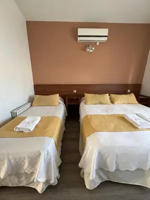 a room with two beds with white sheets at Casa Piedra Hotel in Villa Carlos Paz