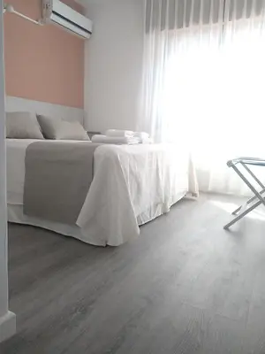 a white bedroom with a bed and a window at Casa Piedra Hotel in Villa Carlos Paz