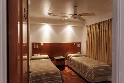 a hotel room with two beds and a ceiling fan at Hotel Petit in Cordoba