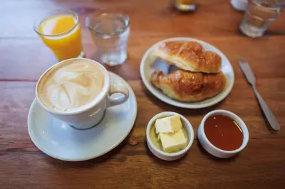 a table with a cup of coffee and a plate of food at Hotel Petit in Cordoba