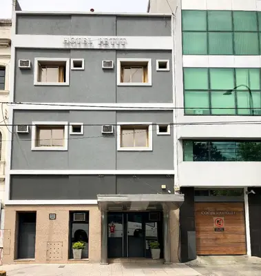 a tall gray building with windows and doors at Hotel Petit in Cordoba