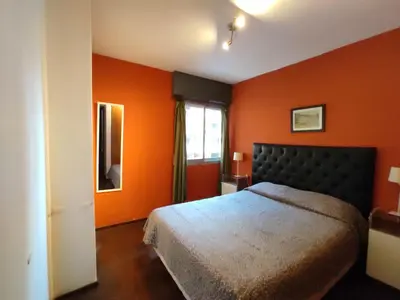 a bedroom with orange walls and a bed and a window at Apartamento Pueyrredón in Cordoba