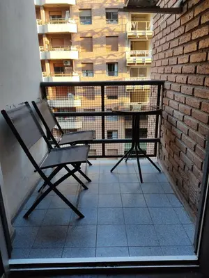 a chair and a table on a balcony with a building at Apartamento Pueyrredón in Cordoba