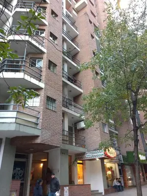 a tall brick building with people walking in front of it at Apartamento Pueyrredón in Cordoba