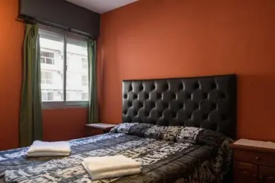 a bedroom with a bed with a black headboard and a window at Apartamento Pueyrredón in Cordoba