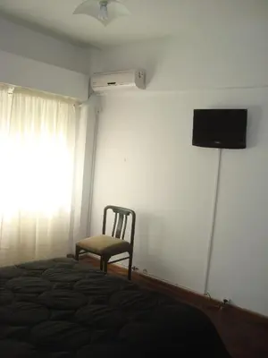 a bedroom with a bed and a chair and a window at Departamento sobre principal calle PEATONAL plena zona Finaciera y Comercial in Cordoba