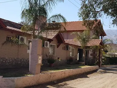 a house with a palm tree in front of it at Apart Hotel Piscu Yaco in Merlo