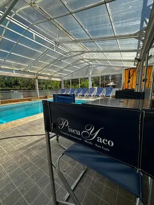 a table with chairs and a pool in a building at Apart Hotel Piscu Yaco in Merlo