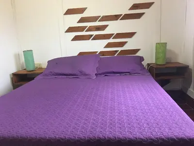 a purple bed in a bedroom with two tables at Sol de Bach in Tanti