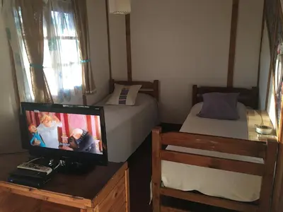 a small room with two beds and a tv and a desk at Sol de Bach in Tanti