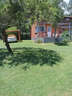 a shady yard with a tree and a house at al pie del morro in Merlo