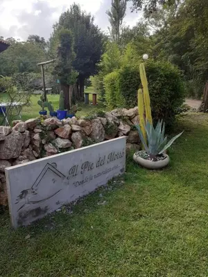 a sign in the grass next to a rock wall at al pie del morro in Merlo