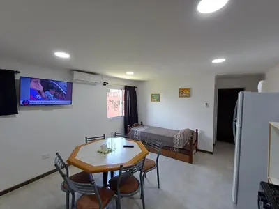 a living room with a table and a room with a bed at La Villa Inn in Villa Carlos Paz