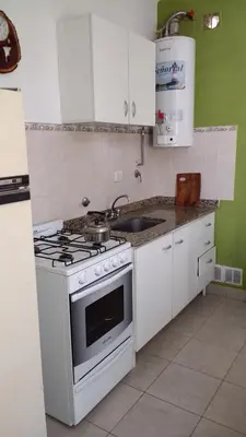 a white kitchen with a stove and a sink at Complejo ARABELA in Merlo