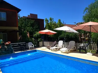 a swimming pool with two umbrellas and two chairs at Complejo ARABELA in Merlo