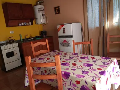 a kitchen with a table and a white refrigerator at Complejo ARABELA in Merlo