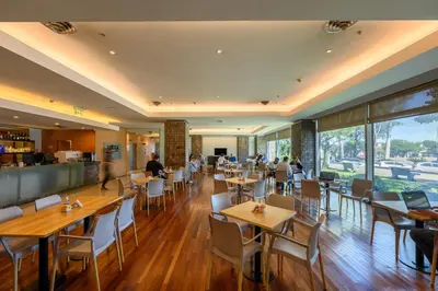 a restaurant with wooden tables and white chairs at Orfeo Suites Cordoba in Cordoba