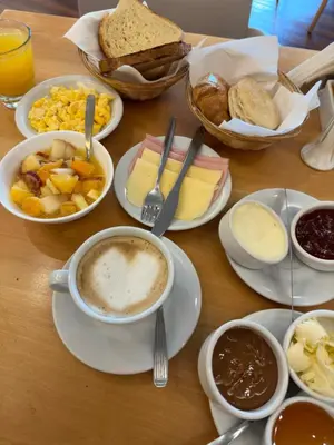 a table with plates of food and a cup of coffee at Orfeo Suites Cordoba in Cordoba