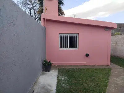 a pink house is next to a wall at Departamento Manna in Alta Gracia