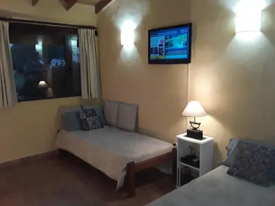 a bedroom with a bed and a tv on the wall at Cabanas Vista Hermosa in Santa Rosa de Calamuchita