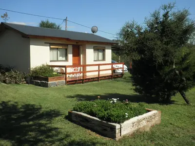 a house with a yard with a flower bed in front of it at Cabanas Vista Hermosa in Santa Rosa de Calamuchita
