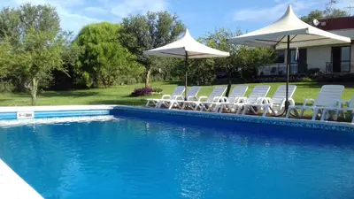 a group of chairs and umbrellas next to a pool at Cabanas Vista Hermosa in Santa Rosa de Calamuchita