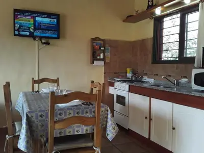 a kitchen with a table and a tv on the wall at Cabanas Vista Hermosa in Santa Rosa de Calamuchita