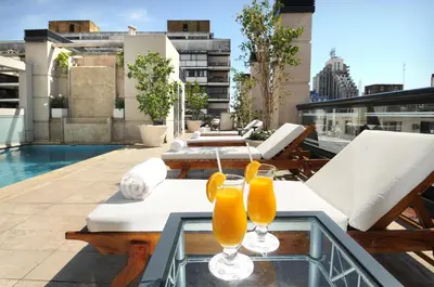 two glasses of orange juice on a glass table on a balcony at Windsor Hotel in Cordoba