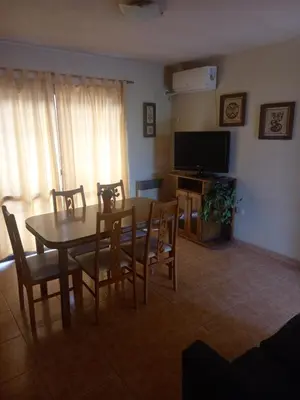 a living room with a table and chairs and a television at Complejo Camila in Villa Carlos Paz
