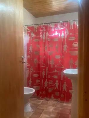 a bathroom with a red shower curtain and a sink at La Casa de Don Pepe in Villa de Las Rosas