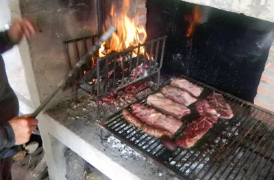 a person is cooking meat on a grill at La Casa de Don Pepe in Villa de Las Rosas