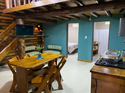a kitchen with a wooden table and chairs in a room at Suenos del Bosque ApartHotel in Atos Pampa