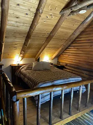 a bed in a room with a wooden ceiling at Suenos del Bosque ApartHotel in Atos Pampa