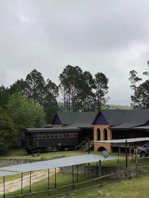 a barn with a black roof and a building at Suenos del Bosque ApartHotel in Atos Pampa