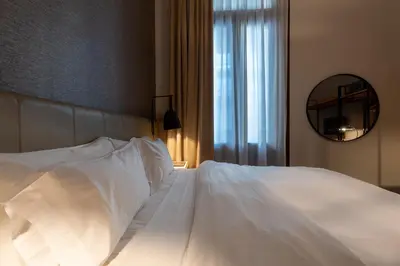 a bed with white sheets and a mirror in a bedroom at Azur Hotel & Spa in Cordoba