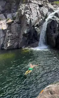 a person swimming in the water in front of a waterfall at Merlo 1 in Merlo