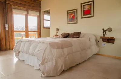 a bedroom with a bed with a white comforter at Cabañas Agalma in Villa Yacanto