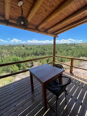 a wooden table and a chair on a wooden deck at Cabañas Agalma in Villa Yacanto