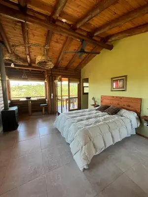 a large bed in a large room with wooden ceilings at Cabañas Agalma in Villa Yacanto