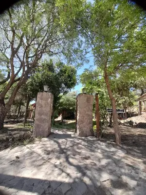 a pair of stone pillars in a park with trees at Complejo de Cabañas Estancia Del Águila in Mina Clavero