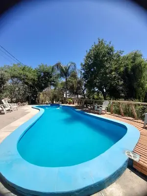 a large blue swimming pool with a wooden deck at Complejo de Cabañas Estancia Del Águila in Mina Clavero